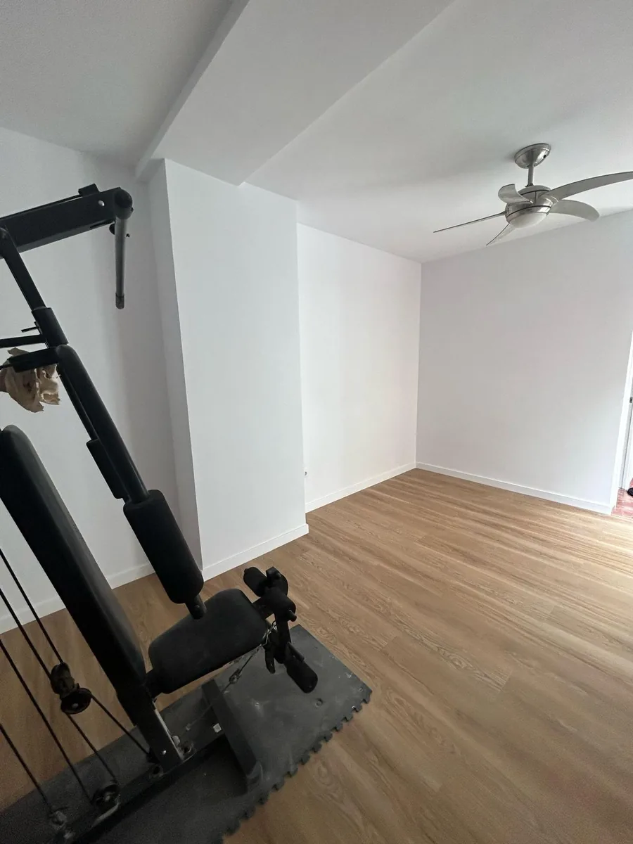 Salón con suelo nuevo y ventilador de techo tras una reforma de piso en Valencia